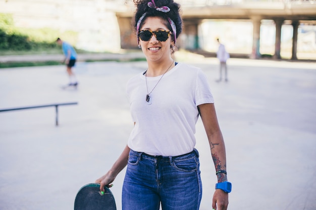 Girl holding skateboard standing on street