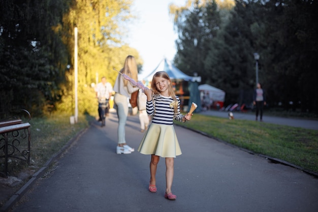 Girl holding a stick with sugar cloud and an ice cream cone