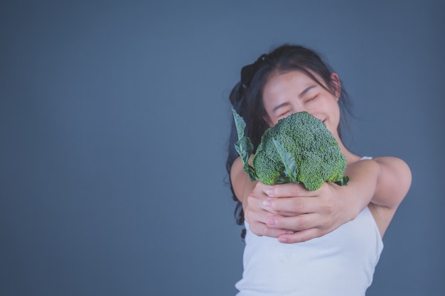 Girl holds the vegetables on a gray background.