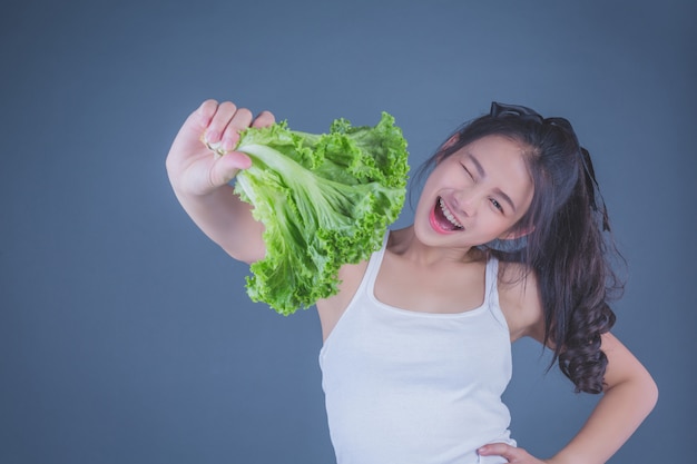 Girl holds the vegetables on a gray background.