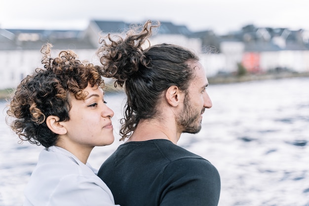 Girl hugging her partner  back with the  sea out of focus