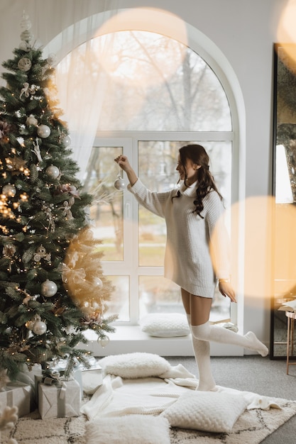 Girl is hanging a toy on a Christmas tree