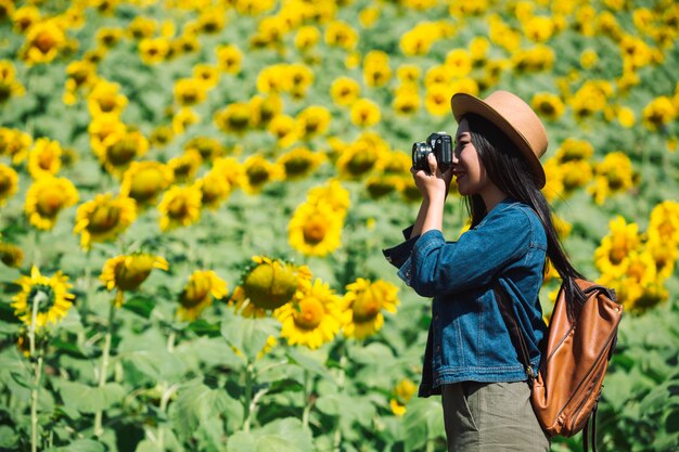 The girl is happy to take pictures in the sunflower field.