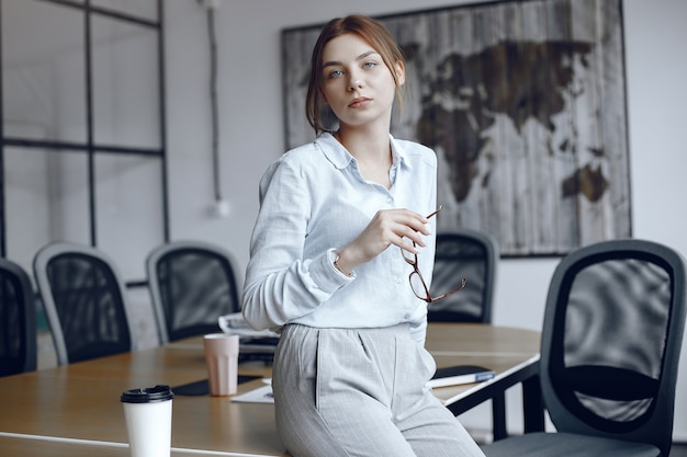 Girl  is sitting at the table.Woman holding glasses in her hands.Beauty looks at the camera