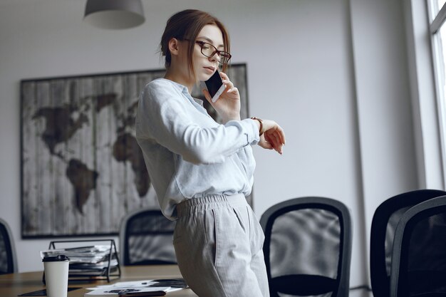 Girl is standing by the window.Woman talking on the phone.Brunette looks at her watch