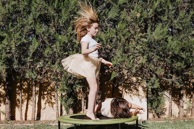 Free photo girl jumping on trampoline near lying sister