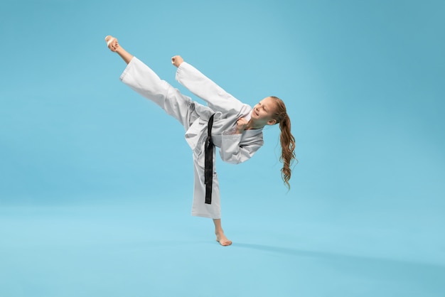 Girl in kimono practicing kick foot forward.