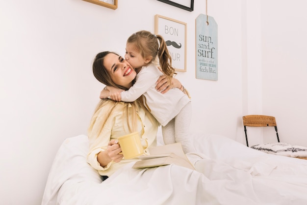 Free photo girl kissing reading mother in morning