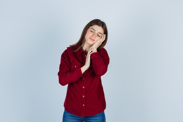 girl leaning cheek on palm, shutting eyes in casual shirt and looking sleepy