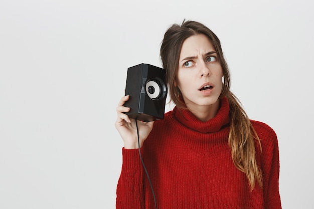 Girl leaning to speaker, listen to sound carefully