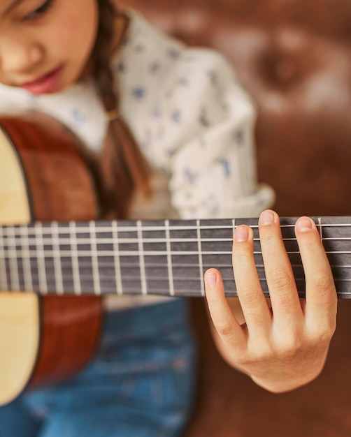 Girl learning how to play guitar at home