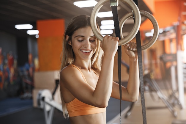 Free photo girl likes holdingcrossfit gymnastics rings, smiling delighted.