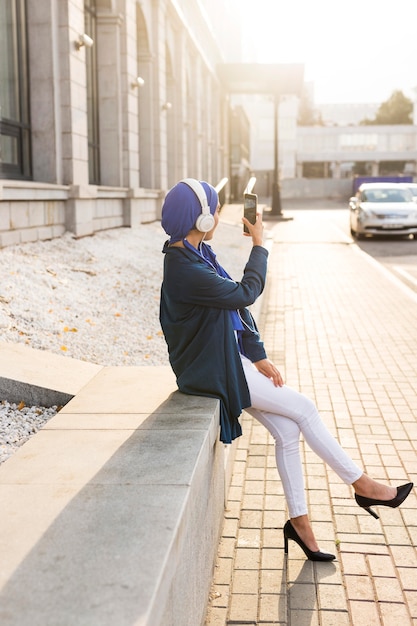 Girl listening to music through headphones outside with copy space