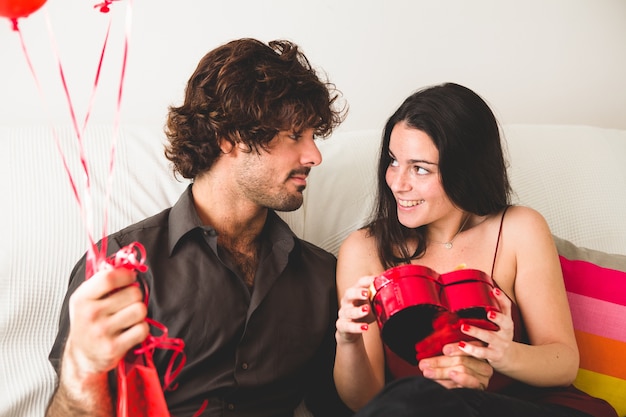 Girl looking at her boyfriend while opening a box of chocolates