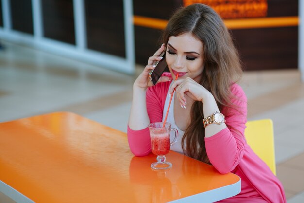 Girl looking at her soda while talking on the phone