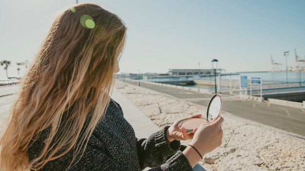 Free Photo girl looking into small mirror at harbor