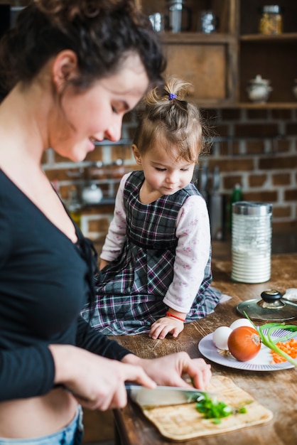 Free Photo girl looking at mother cutting onion