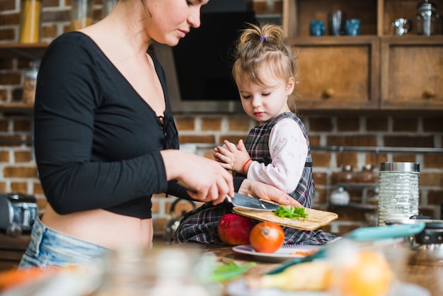 Free Photo girl looking at mother making salad