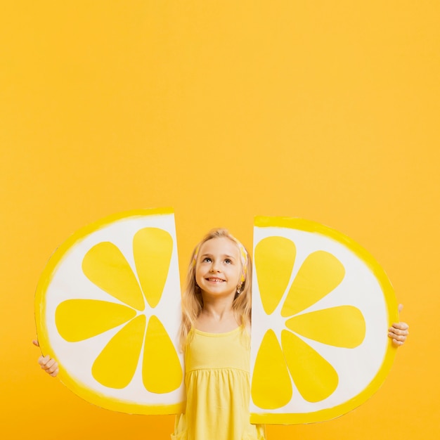 Girl looking up while holding lemon slices decorations