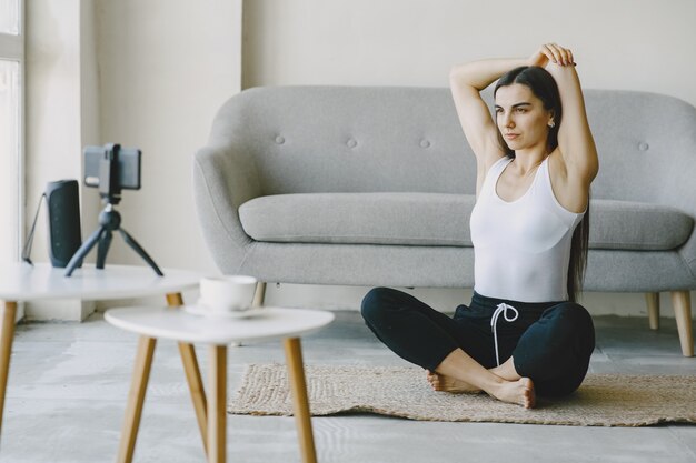 Girl looks at phone. Yogi kneading. Woman at home in a sports clothes.