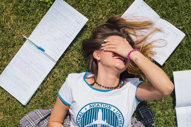 Girl lying on grass covering face