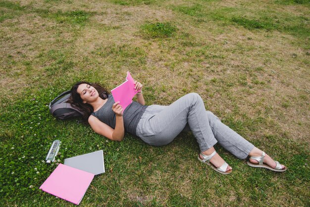 Girl lying on grass reading notebook