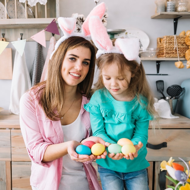 Girl and mother in bunny ears holding Easter eggs in hands 