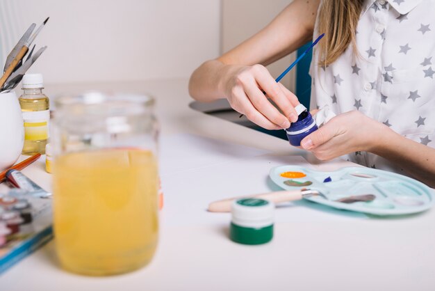 Girl opening blue gouache can at table