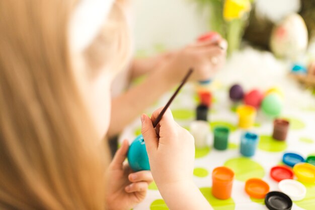 Girl painting egg with mother