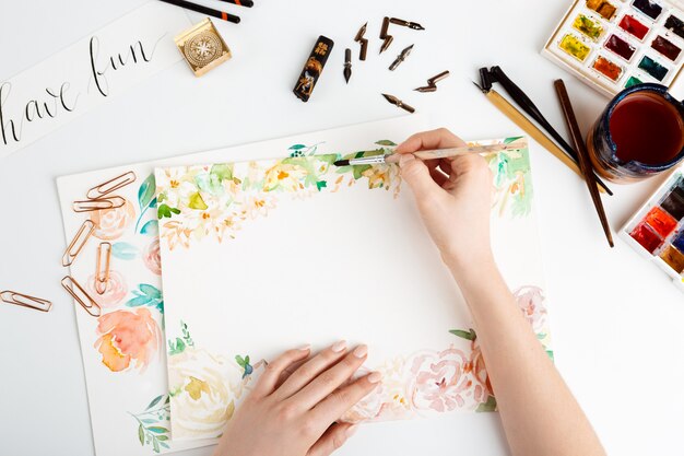 Girl painting flowers on paper with watercolor.