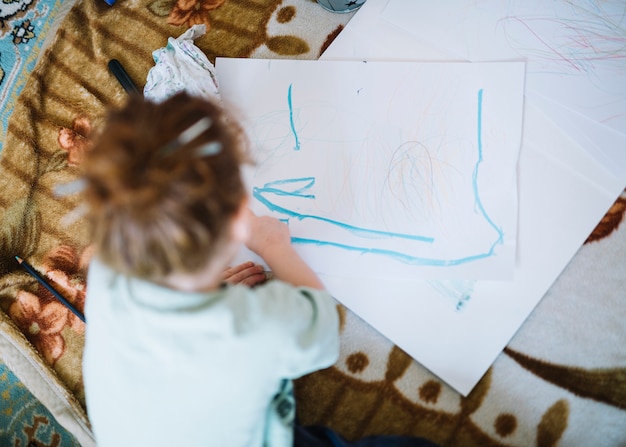 Free photo girl painting on paper and sitting on floor