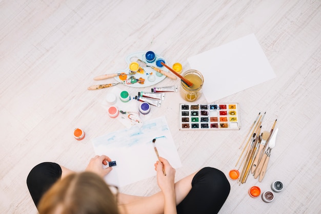 Free Photo girl painting with bright aquarelle on floor