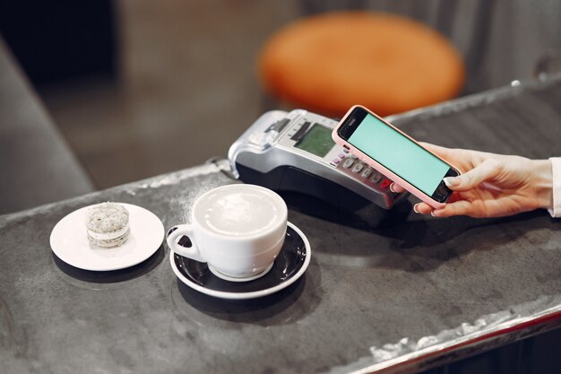 Girl paying for her latte with a smartphone by contactless PAY PASS technology