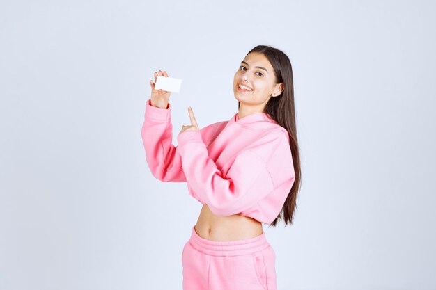 Girl in pink pajamas holding a business card and introducing herself to her business partners. 