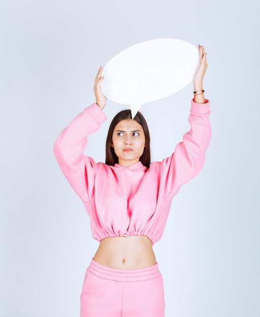 Girl in pink pajamas holding a round think board and dislike it. 