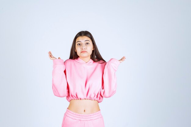 Girl in pink pajamas looks confused and unexperienced