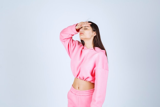 Girl in pink pajamas looks tired and sleepy