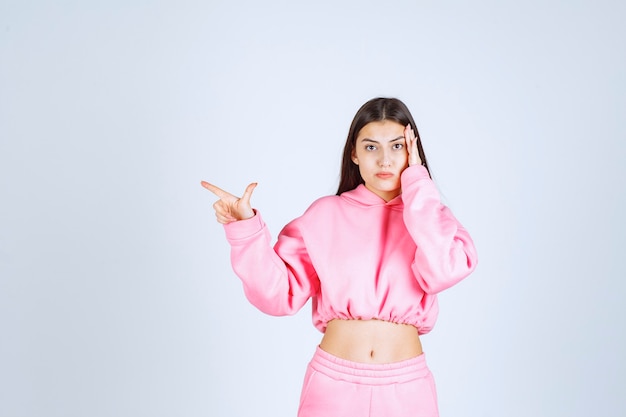 Girl in pink pajamas pointing at something on the left