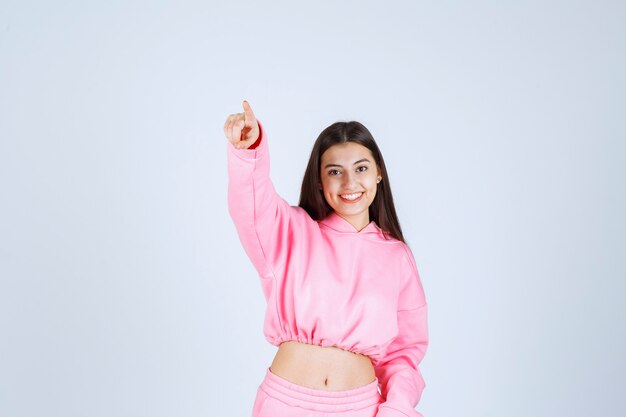 Girl in pink pajamas pointing to somewhere. 