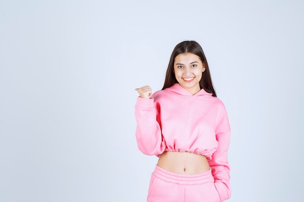 Girl in pink pajamas pointing to somewhere. 