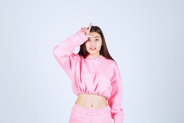 Girl in pink pajamas showing loser sign