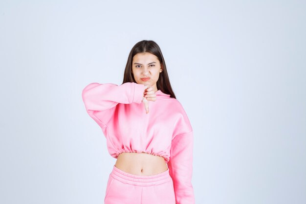 Girl in pink pajamas showing thumb down sign. 