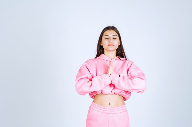 Girl in pink pajamas uniting her hands and praying