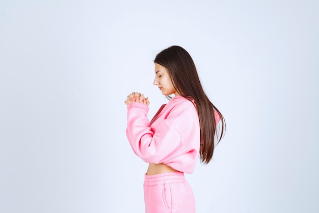 Girl in pink pajamas uniting her hands and praying