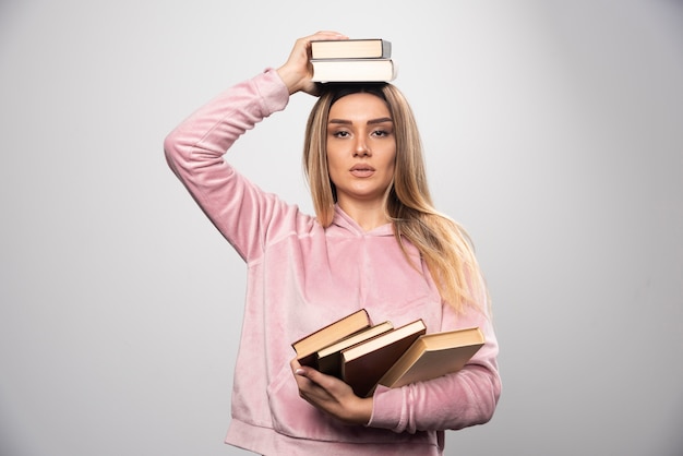 Free photo girl in pink swaetshirt holding her books over her head.