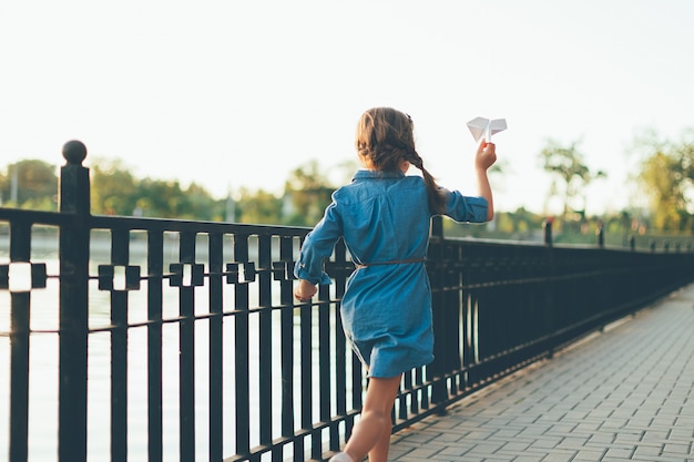 Girl playing, running with toy paper airplane