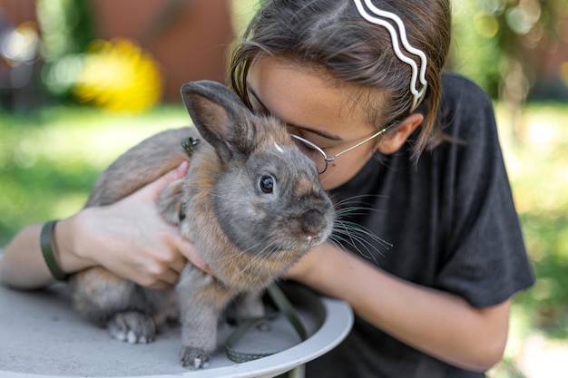 A girl plays with a domestic rabbit on the street pet concept