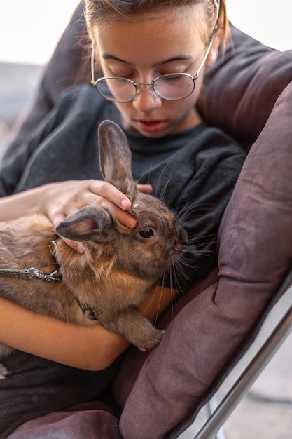 A girl plays with a domestic rabbit on the street pet concept