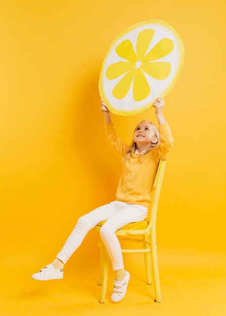 Free photo girl posing while holding up lemon slice decoration