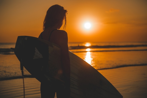 Free photo girl posing with a board at sunset